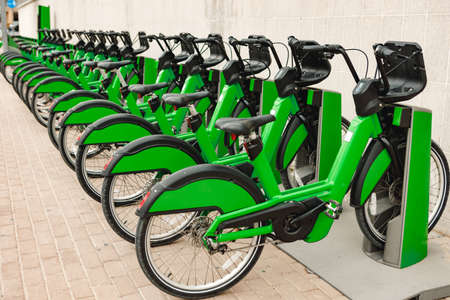 Green bicycles for rent stand in row on street