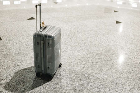 Gray travel suitcase in empty airport hallの写真素材