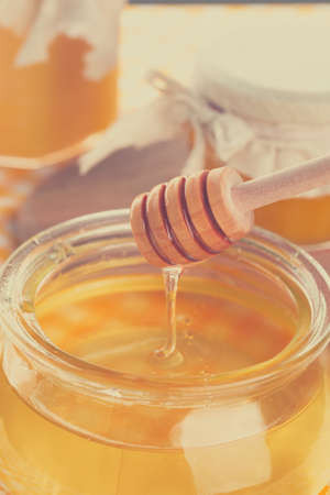 Honey background. Sweet honey in glass jar on wooden background.の写真素材