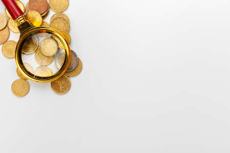 Magnifier and coins on white background