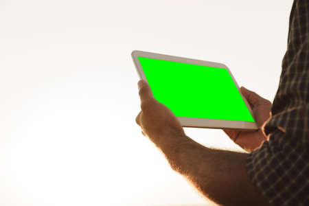 Close up of farmer's hands holding tablet with green isolated screenの写真素材