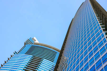Glass skyscraper building with cloudy blue sky background
