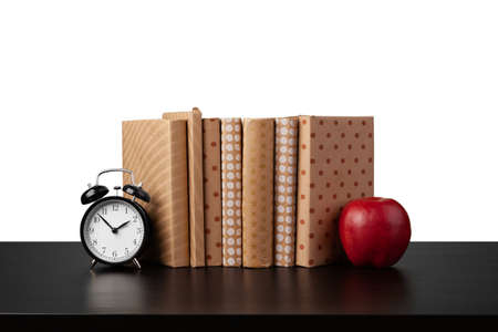 Stack of books and apple on tabletop against white background