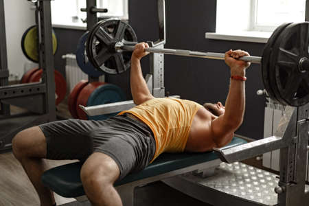 Bearded man bodybuilder doing bench press exercise in gym