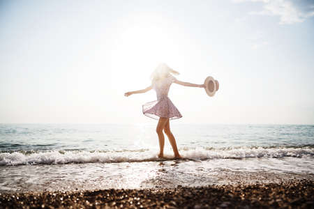 Lonely young woman walks on the seashore at sunsetの写真素材