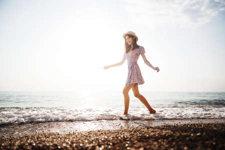 Portrait of young woman walking on the beach on sunriseの写真素材