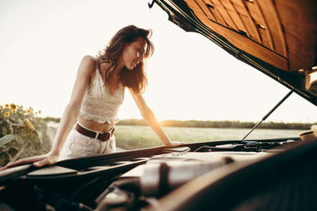 Young woman opening the bonnet of her broken car in the countrysideの写真素材