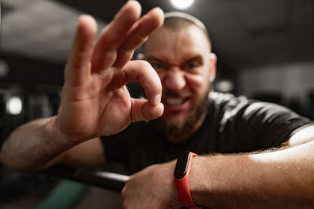 Cheerful smiling man bodybuilder standing in a gym