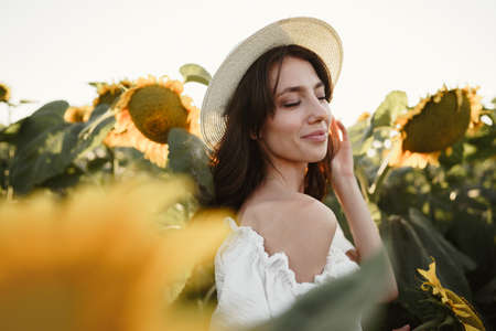 Attractive young woman model posing in field of sunflowersの写真素材