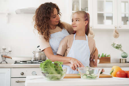 Mother and teen daughter preparing vegetable salad at kitchenの写真素材