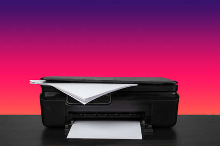 Home laser printer on desk against purple background
