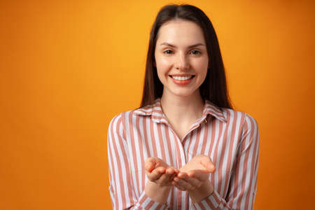 Woman showing something and offering against yellow backgroundの写真素材