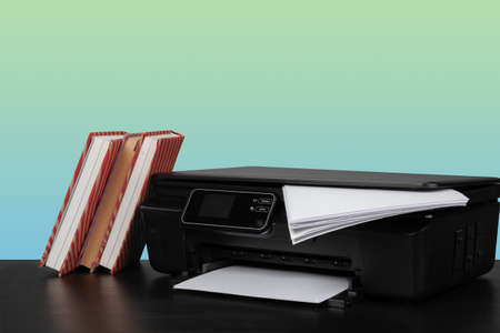 Home laser printer on desk against green background