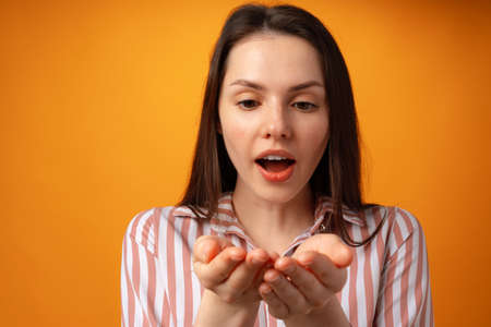 Woman showing something and offering against yellow backgroundの写真素材
