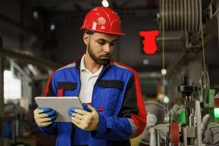 African american male manager in electric cable warehouse holding digital tablet