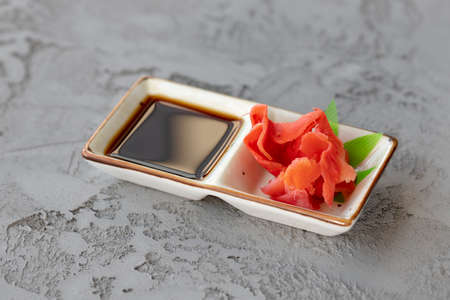 Soy sauce and marinated ginger in plate on gray tableの写真素材