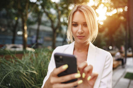 Beautiful young blonde businesswoman using smartphone in the cityの写真素材