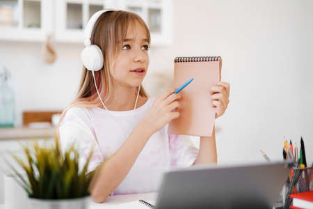 Homeschooled little young girl student having online class using digital tablet