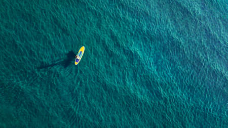 Aerial photo of man on sup board in clear blue seaの写真素材
