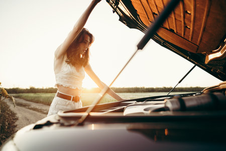 Young woman opening the bonnet of her broken car in the countrysideの写真素材