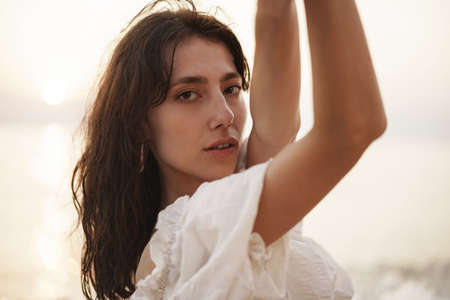Portrait of young brunette haired woman at the beach at sunset