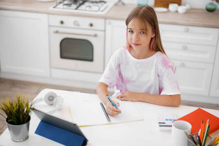 Homeschooled little young girl student having online class using digital tabletの写真素材