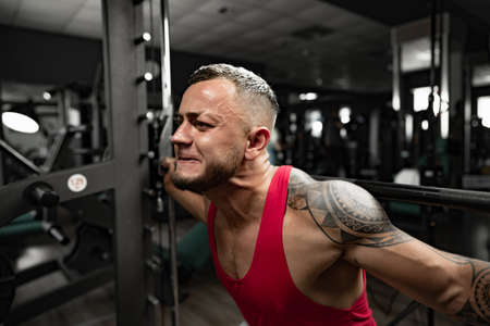 Portrait of man bodybuilder in red shirt in gym