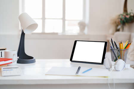 White working table with blank screen digital tablet