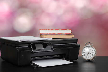 Stack of books and home printer against blurred backgroundの写真素材