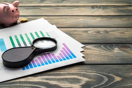 Business graphs and magnifying glass on tableの写真素材