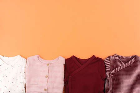 Clothes of baby girl on orange background top view