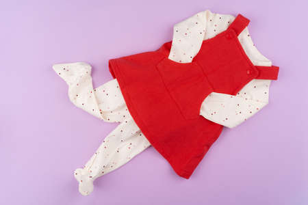 Baby girl clothes on lilac pastel background