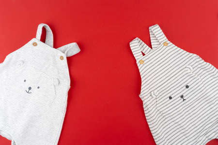 Baby clothes top view on red background