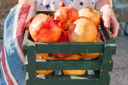 Fresh pomegranates in an old box on wooden backgroundの写真素材