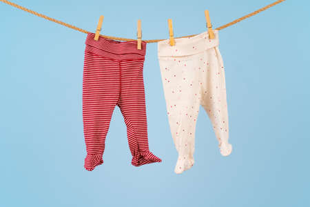 Baby girl clothes pinned on a clothesline against blue backgroundの写真素材