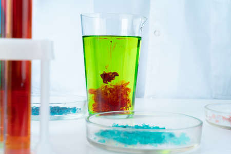 Manipulations with laboratory glass chemical containers on table
