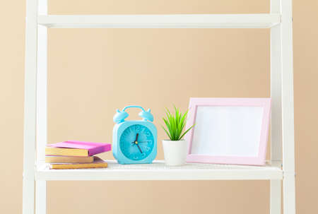 White bookshelf with books and stationery against beige wall