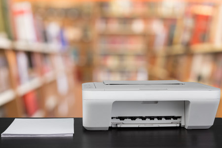 Compact laser printer on black desk against blurred backgroundの写真素材