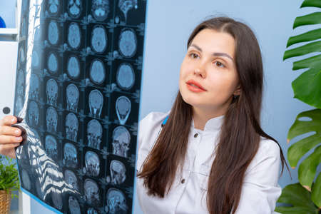 Woman doctor examining patients MR image in her office