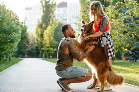 Young happy couple playing with their dog smiling in parkの写真素材