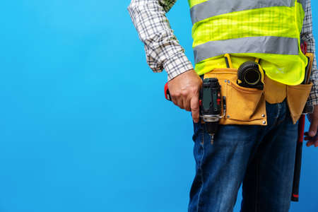 Studio shot of unknown handyman with hands on waist and tool belt with construction toolsの写真素材