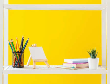 White shelf with stationery objects against bright yellow backgroundの写真素材