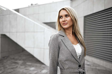 Portrait of young blonde businesswoman in gray suit walking in the cityの写真素材
