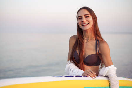 Young woman is carrying paddle board at the beach