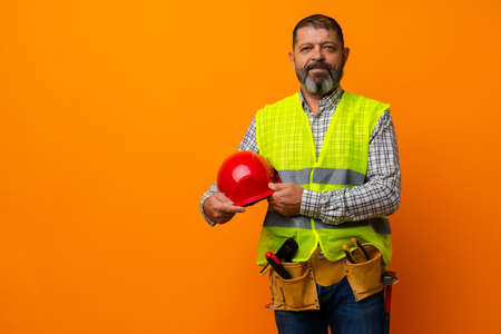 Portrait of senior construction worker in yellow vest in studio