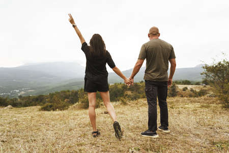 Back view of couple standing and looking at foggy mountains