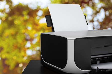 Compact laser printer on black desk against blurred backgroundの写真素材