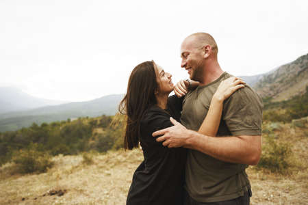 Happy couple in love hugging smiling and having fun in the mountains