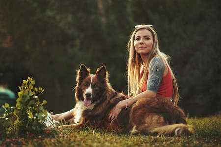 Close up of young female with her dog sitting on grass in parkの写真素材