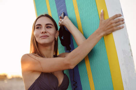Attractive young woman in swimsuit posing with stand up paddle boardの写真素材